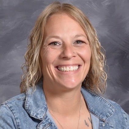 Smiling woman with wavy blonde hair wearing a denim jacket