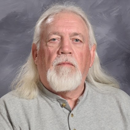 A middle-aged man with long, silver hair and a beard