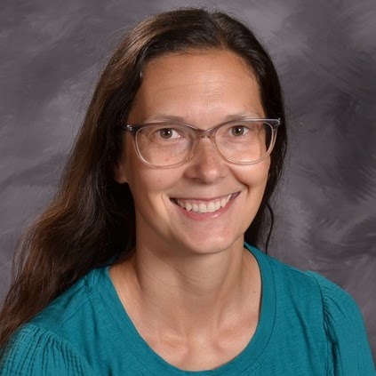 Smiling woman with long dark hair, wearing glasses and a teal shirt