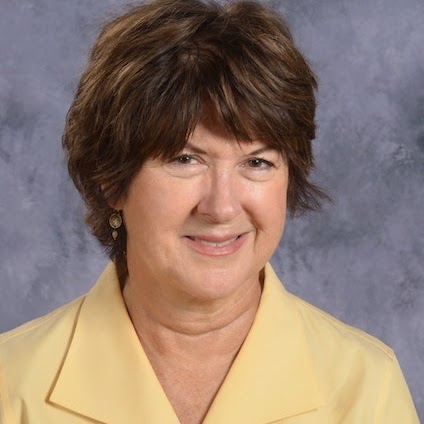 Smiling woman with short, dark hair wearing a yellow blouse