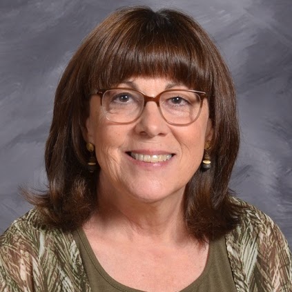 Smiling woman with shoulder-length brown hair and glasses