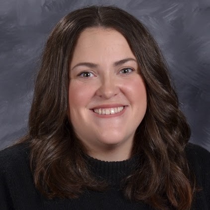 Smiling woman with medium-length, wavy brown hair in a black sweater