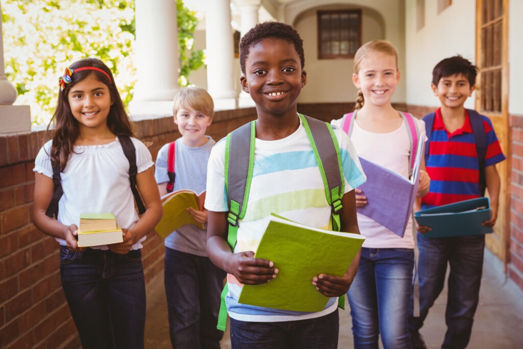 Five diverse students walk together in a school corridor